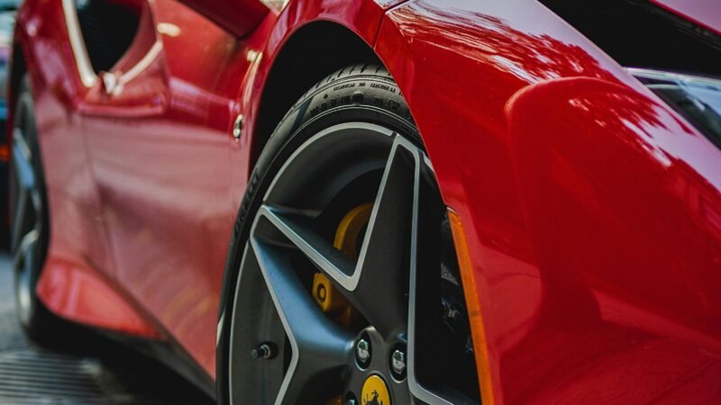 Close-up of a luxurious red sports car parked in a bustling city street.